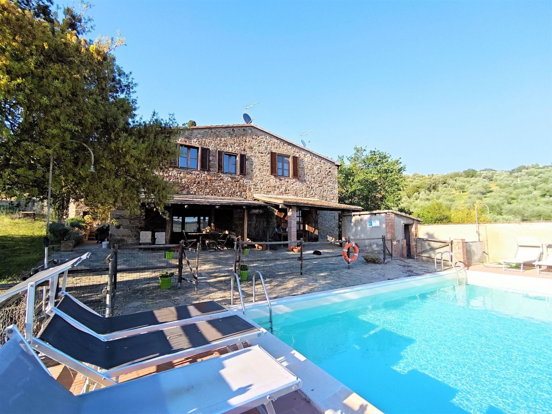 A stone building with a pool, outdoor seating, and a lifebuoy.