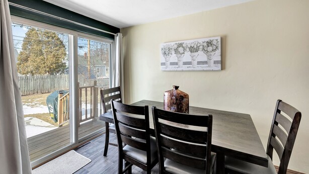 A dining area with a table, chairs, a vase, and a painting on the wall.