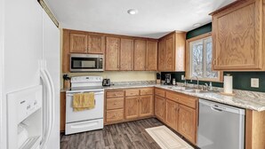 A kitchen with wooden cabinets, a microwave, stove, and dishwasher.