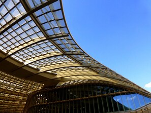 A modern building with a curved glass facade and a large, reflective glass window.