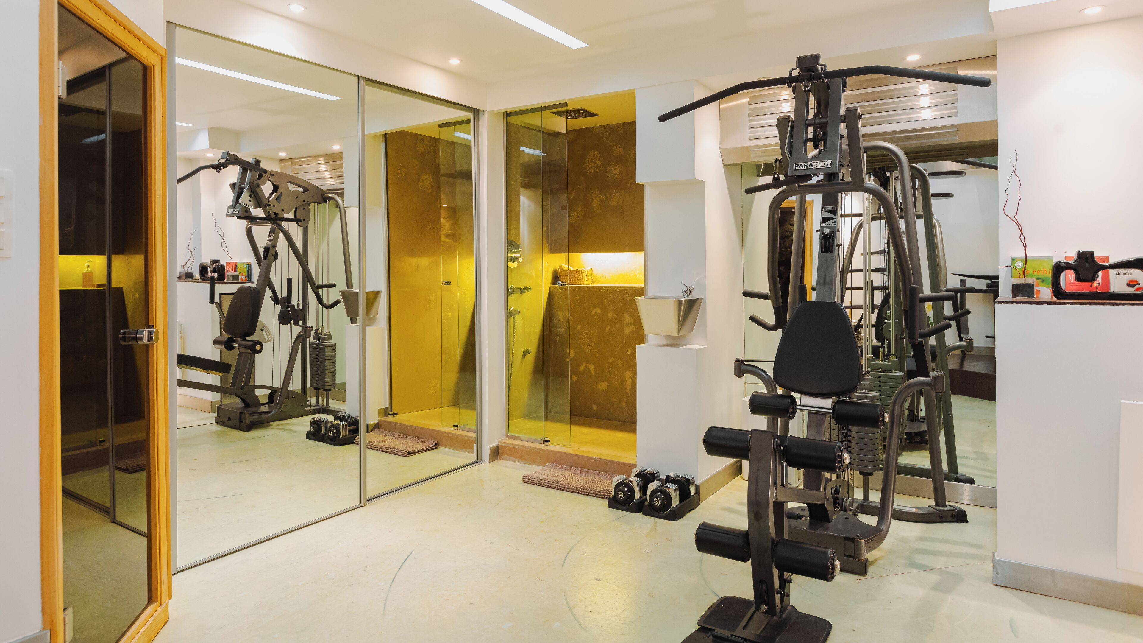 A modern gym with various exercise equipment, glass doors, and a clean, well-lit interior.