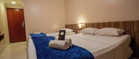 A hotel room with two beds, a wooden headboard, a blue bedspread, and a white door.