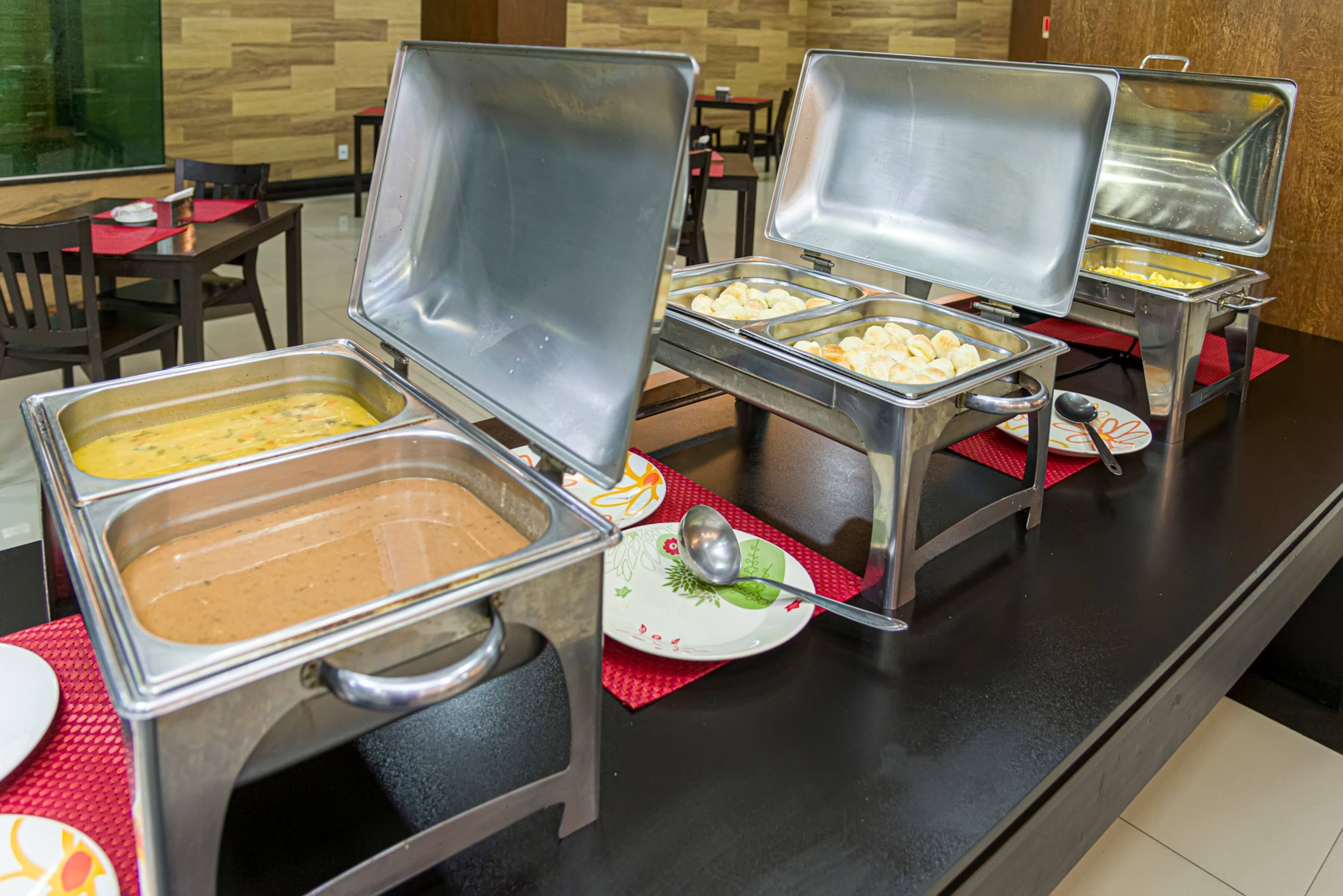 Montaje de bufé con múltiples dispensadores de comida, que incluyen una variedad de platos y una cuchara sobre un plato.