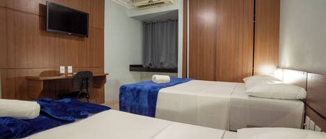 Una habitación de hotel con dos camas, un escritorio, una silla, un televisor y un armario.
