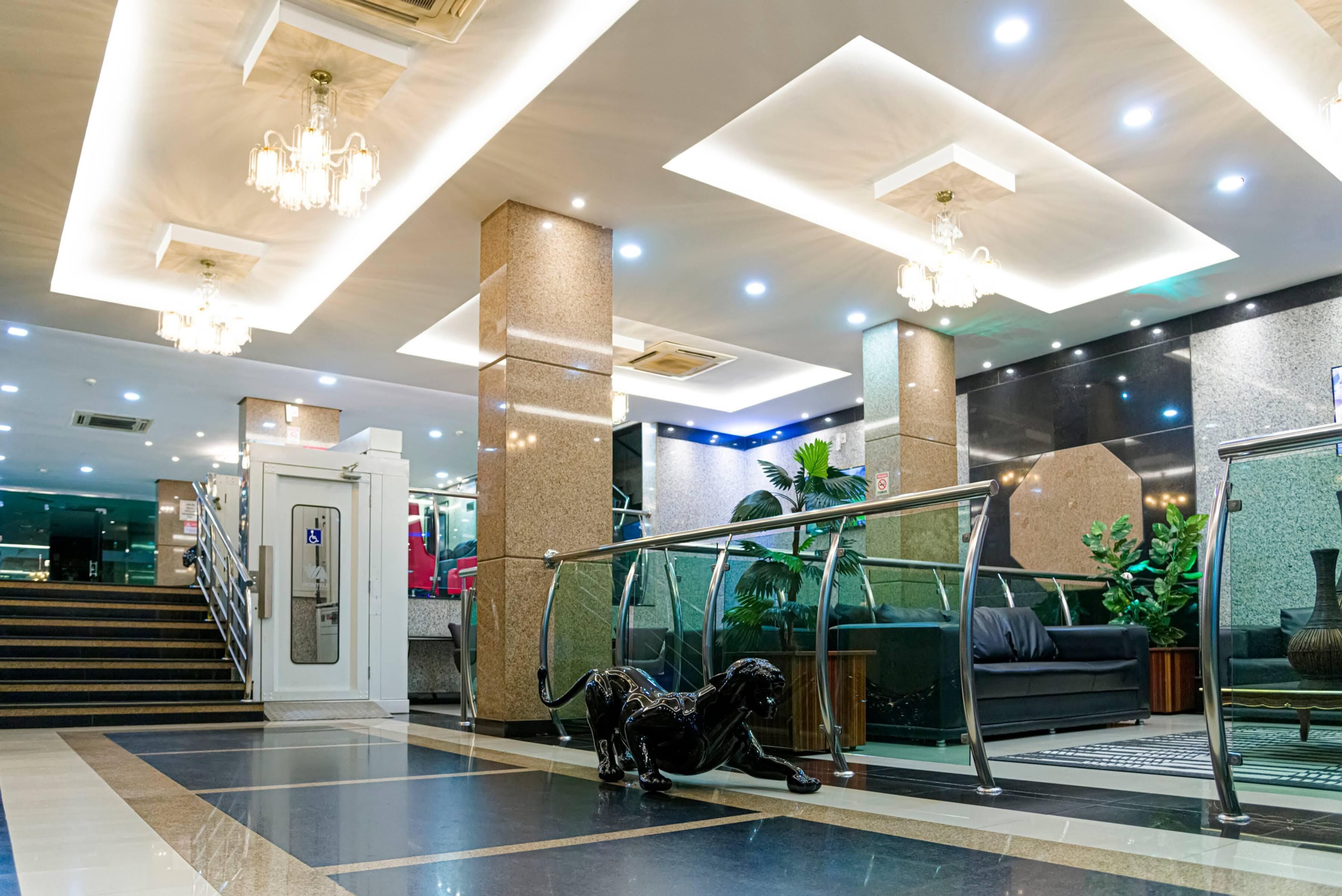 Een moderne lobby met een trap, een receptiebalie en een glazen balustrade.