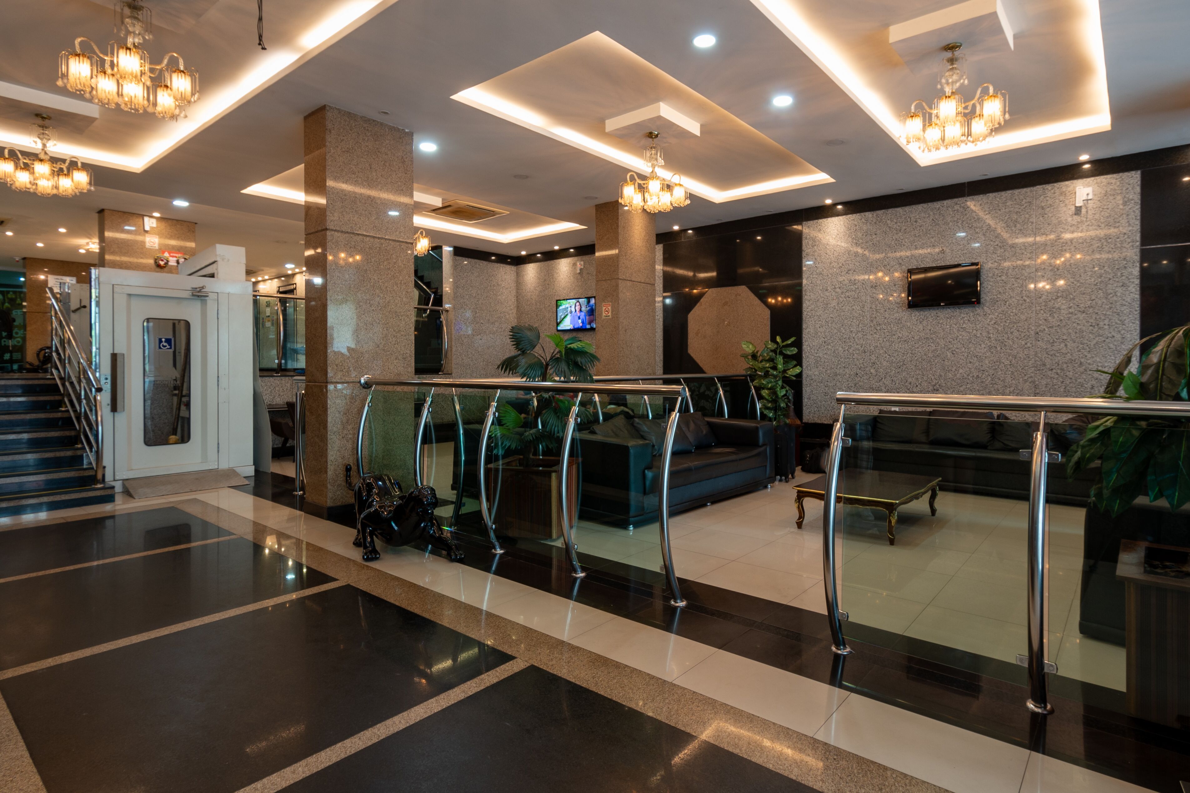 Eine moderne Lobby mit Glastrennwand, Treppe und einem Flachbildfernseher an der Wand.