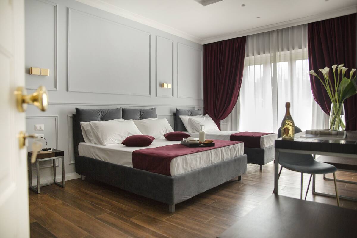 A modern bedroom with a large bed, bedside tables, a desk, and a chair.