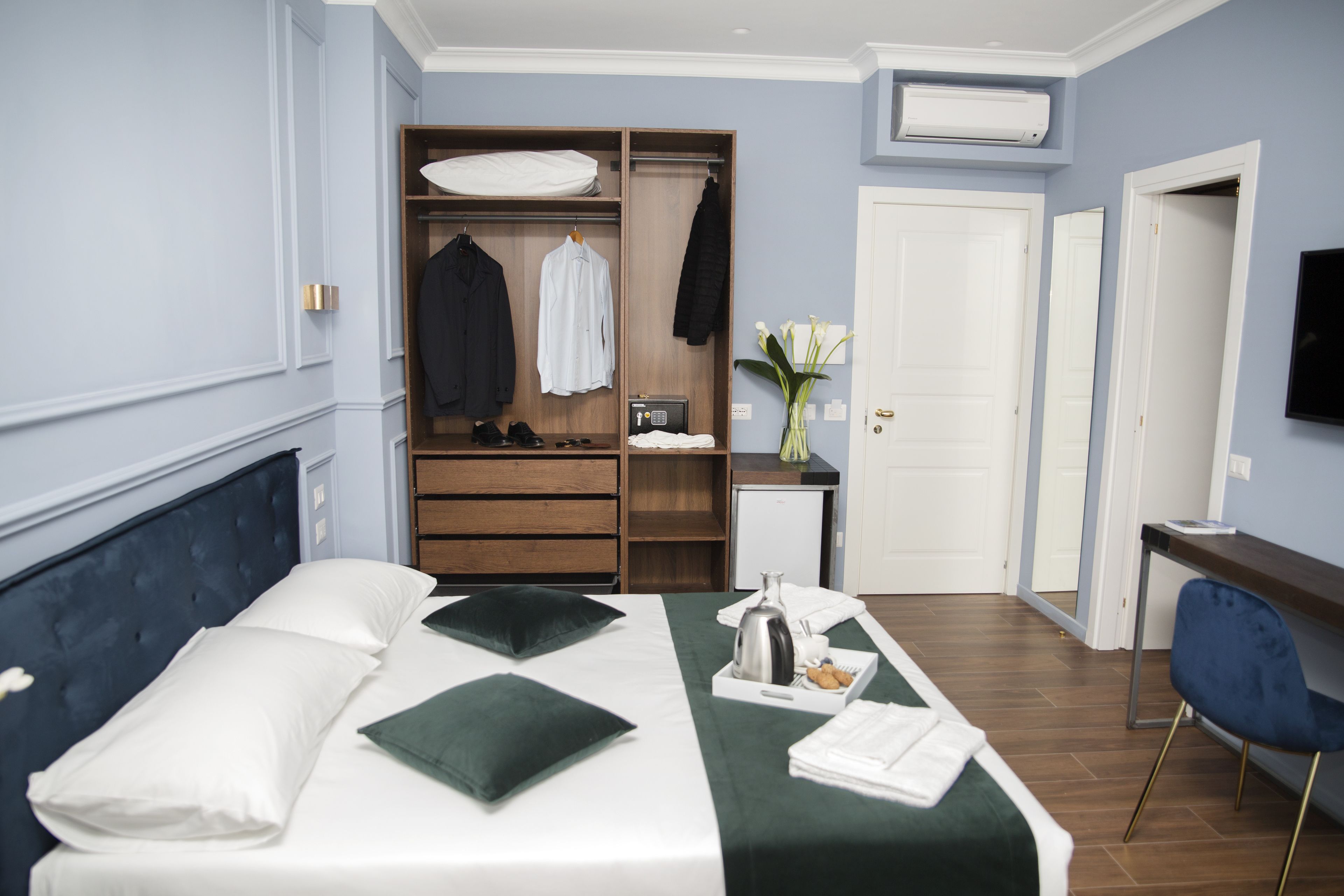 A hotel room with a bed, a desk, a wardrobe, and a TV.