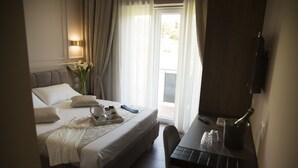 A hotel room with a bed, a desk, a chair, a bottle of champagne, and a vase with flowers. - Unicum Roma Suites (Rome)
