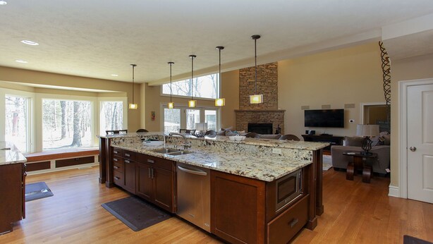 A spacious kitchen with a large island, wooden cabinets, and a stone fireplace. - Experience luxury at Riverwalk, a 4-bedroom retreat in serene Saugatuck, MI. (Saugatuck)