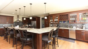 A modern kitchen with a central island, bar stools, and a wine rack. - Experience luxury at Riverwalk, a 4-bedroom retreat in serene Saugatuck, MI. (Saugatuck)
