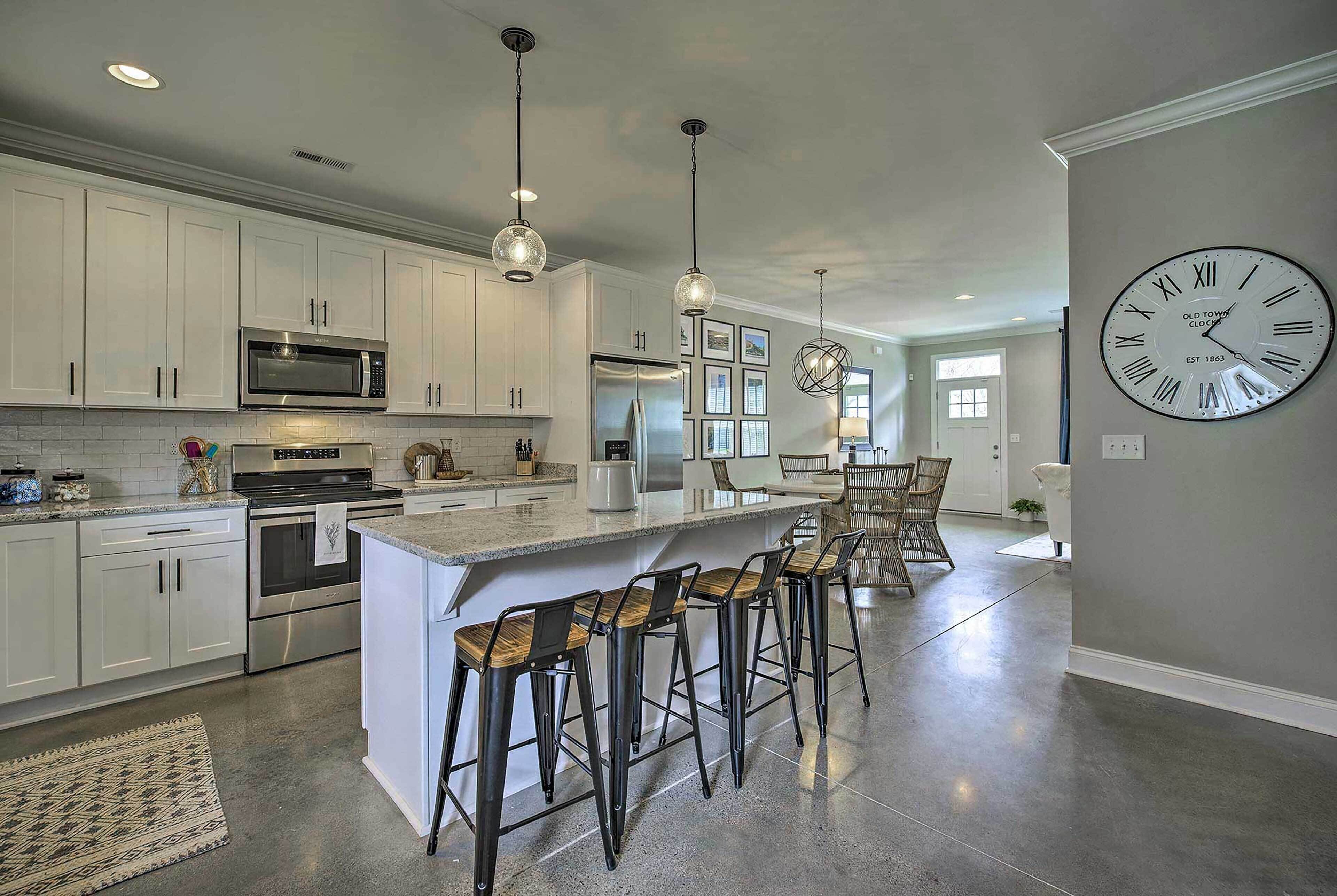 A modern kitchen with white cabinets, stainless steel appliances, and a large island with bar stools.