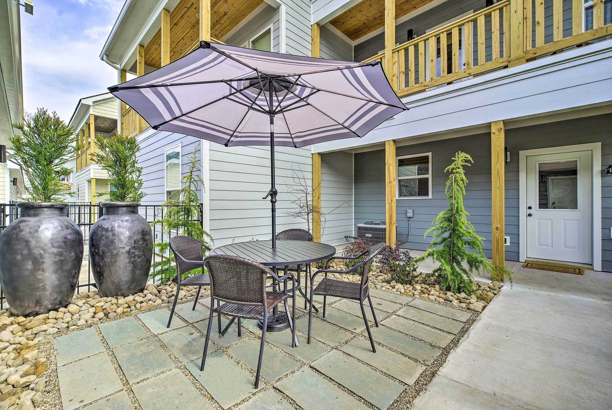 Une terrasse extérieure avec une table et des chaises, un grand parasol et des plantes en pot.