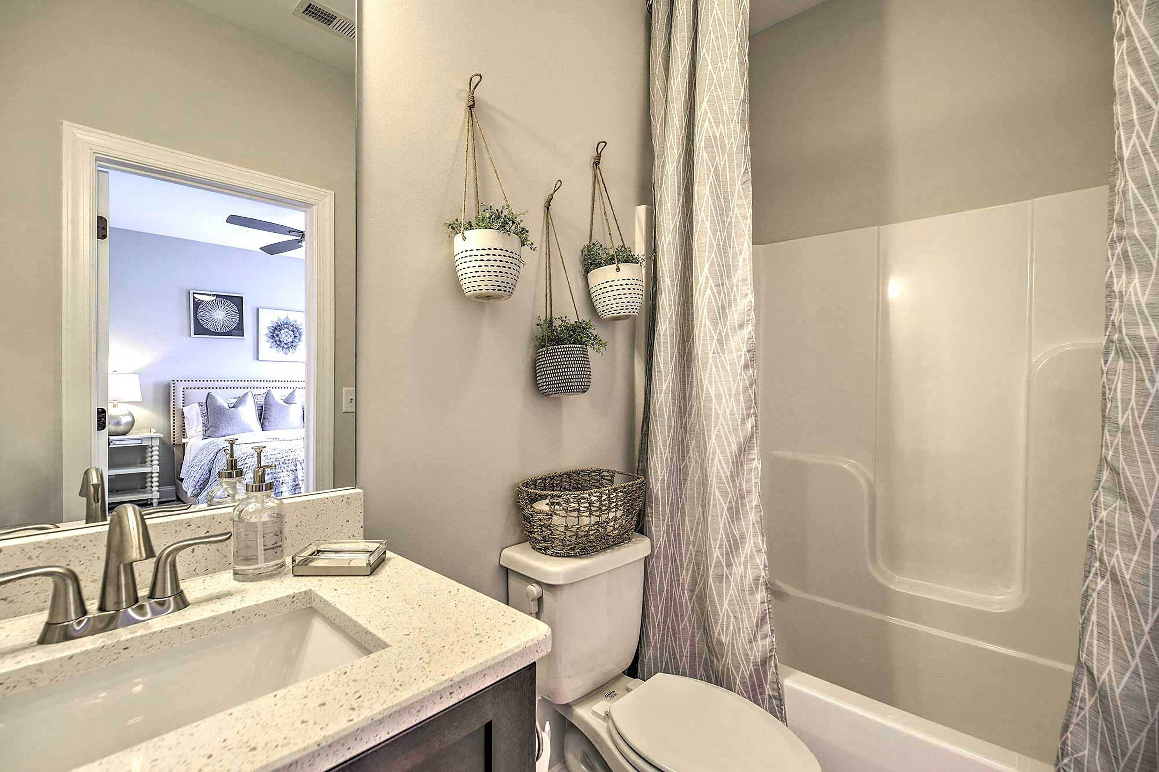 Une salle de bain avec un lavabo, des toilettes et une douche. Trois paniers suspendus sont accrochés au mur.