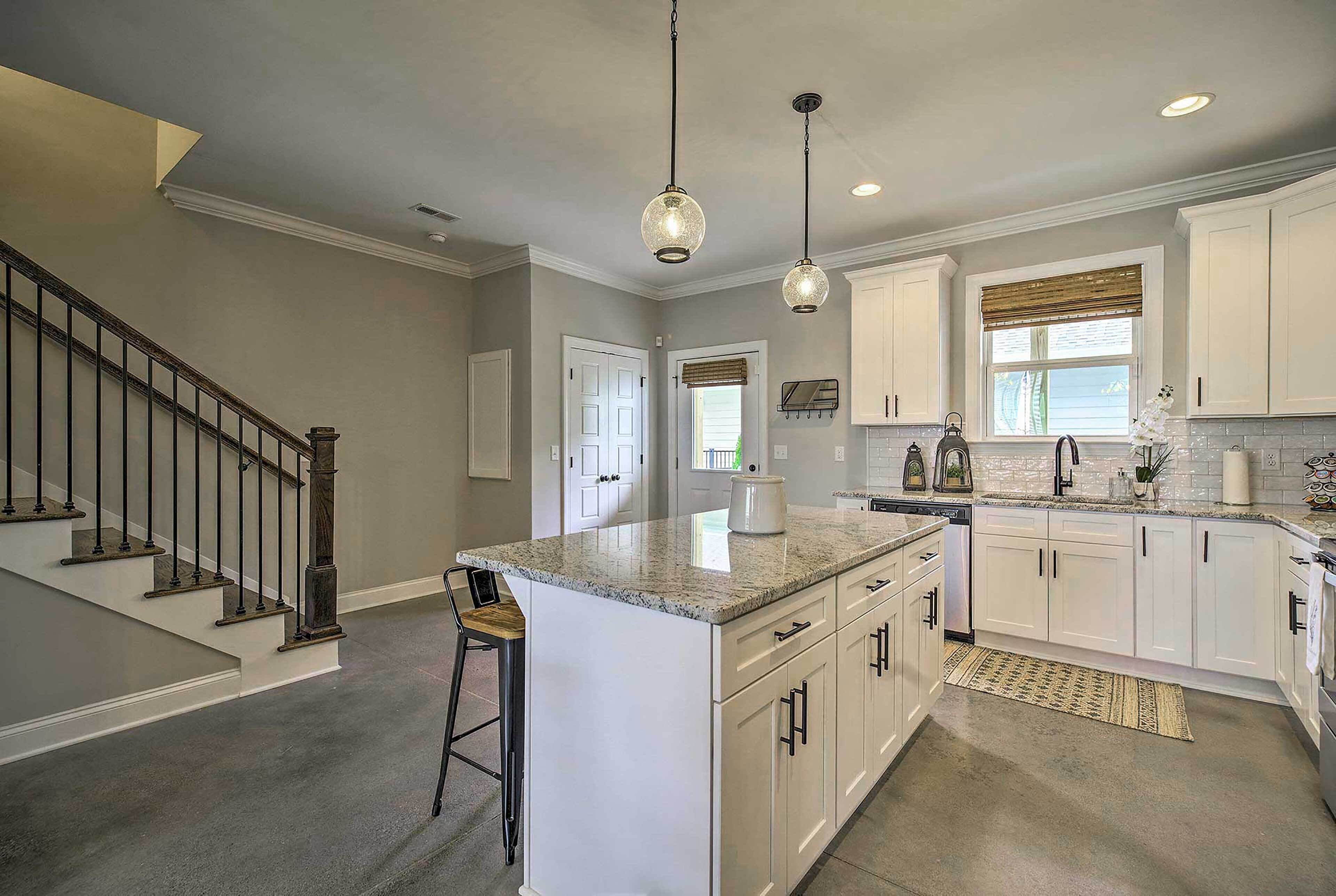 A modern kitchen with white cabinets, a granite countertop, and a central island.
