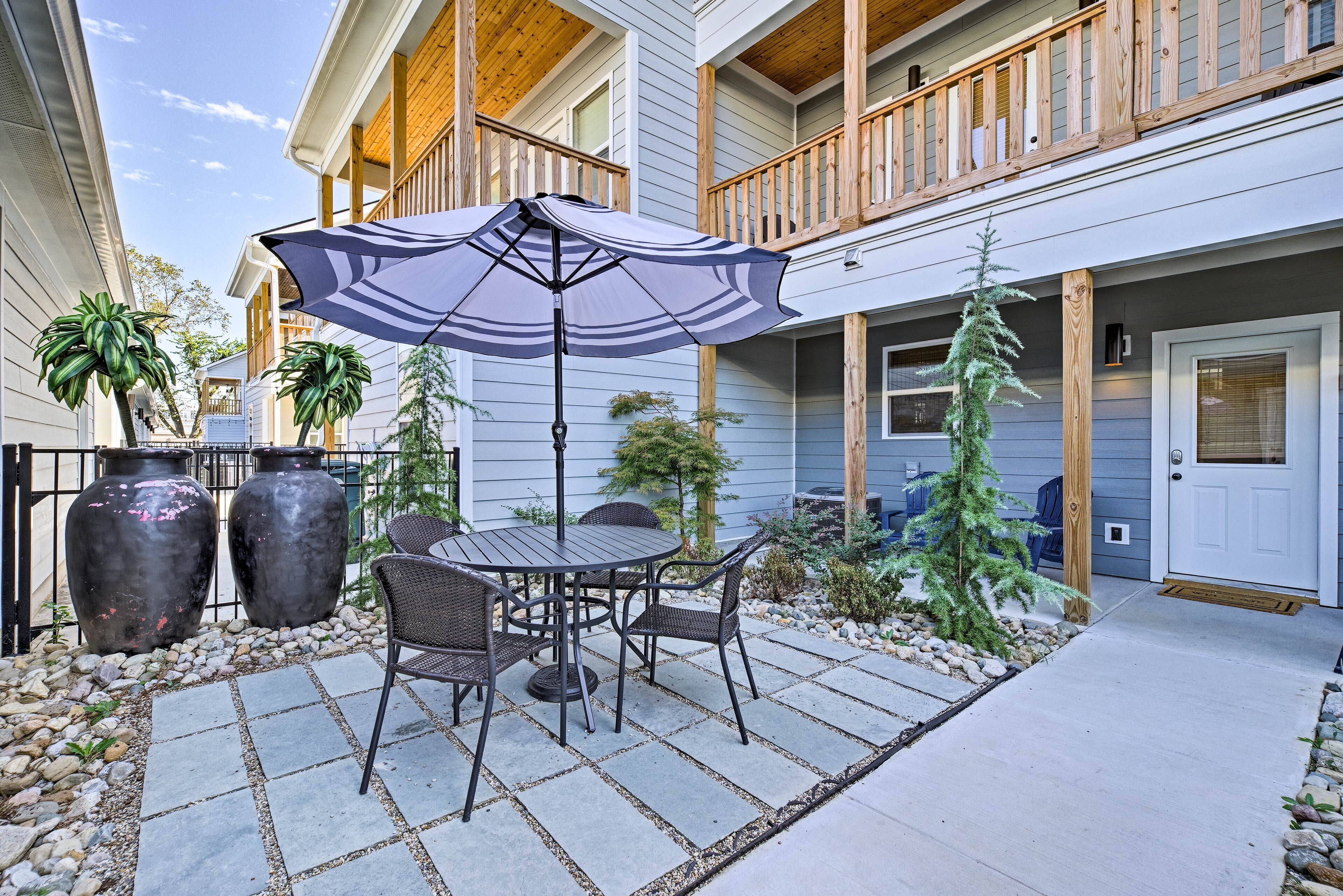 A patio with a table and chairs, an umbrella, and potted plants.