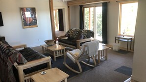 A living room with a sofa, chairs, a small table, and a window with curtains.