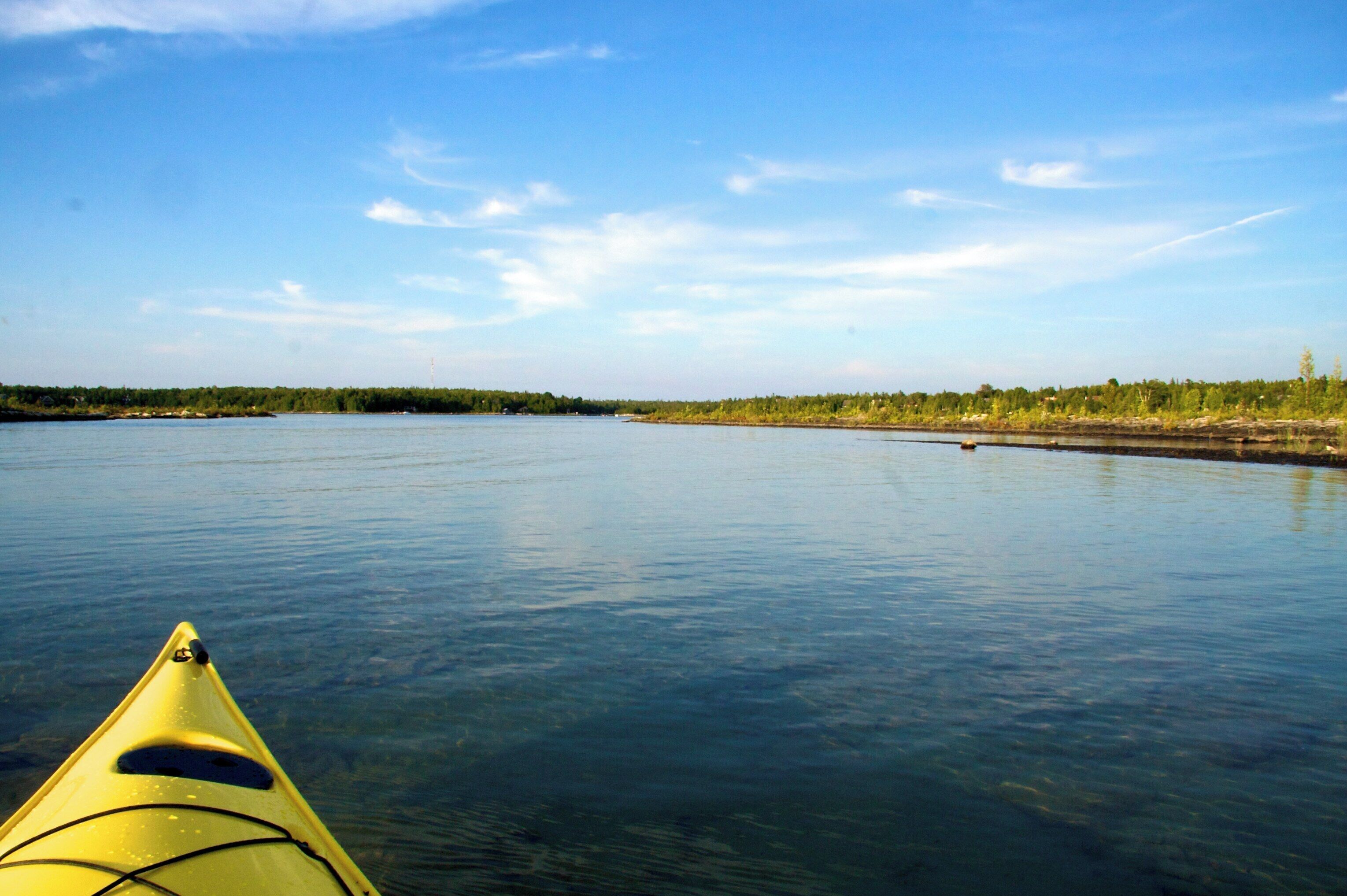 A kayak on a calm river with a forested shoreline.