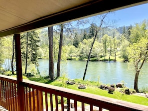 A wooden deck overlooking a river with trees and a grassy area. - *Riverfront*  "Cabin on The Rogue",  Gateway to Crater Lake!  Sleeps 2-4 (Trail)