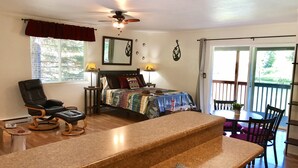 A bedroom with a bed, a chair, a table, and a balcony.