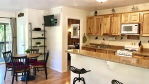 A kitchen with wooden cabinets, a microwave, a stove, and a bar stool.