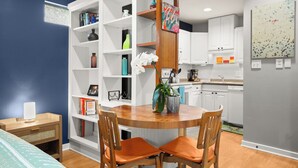 A modern kitchen with white cabinets, a wooden dining table, and orange chairs. - Walk to Restaurants & Shopping; 1 mile to SoCo (Austin)