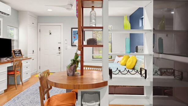 A modern kitchen with white cabinetry, a wooden dining table, and a built-in bookshelf. - Walk to Restaurants & Shopping; 1 mile to SoCo (Austin)