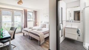 A modern hotel room with a bed, a desk, and a bathroom. - The alternative to a hotel: serviced apartment with garden/kitchen/bathroom/hotel service (Bensheim)