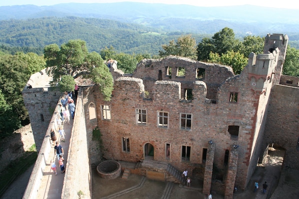 An ancient stone building with a central courtyard, surrounded by a high wall and a pathway for visitors.