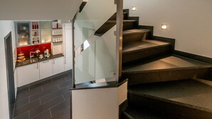 A modern staircase with glass railings and a kitchen area with a red backsplash and white cabinets. - The alternative to a hotel: serviced apartment with garden/kitchen/bathroom/hotel service (Bensheim)