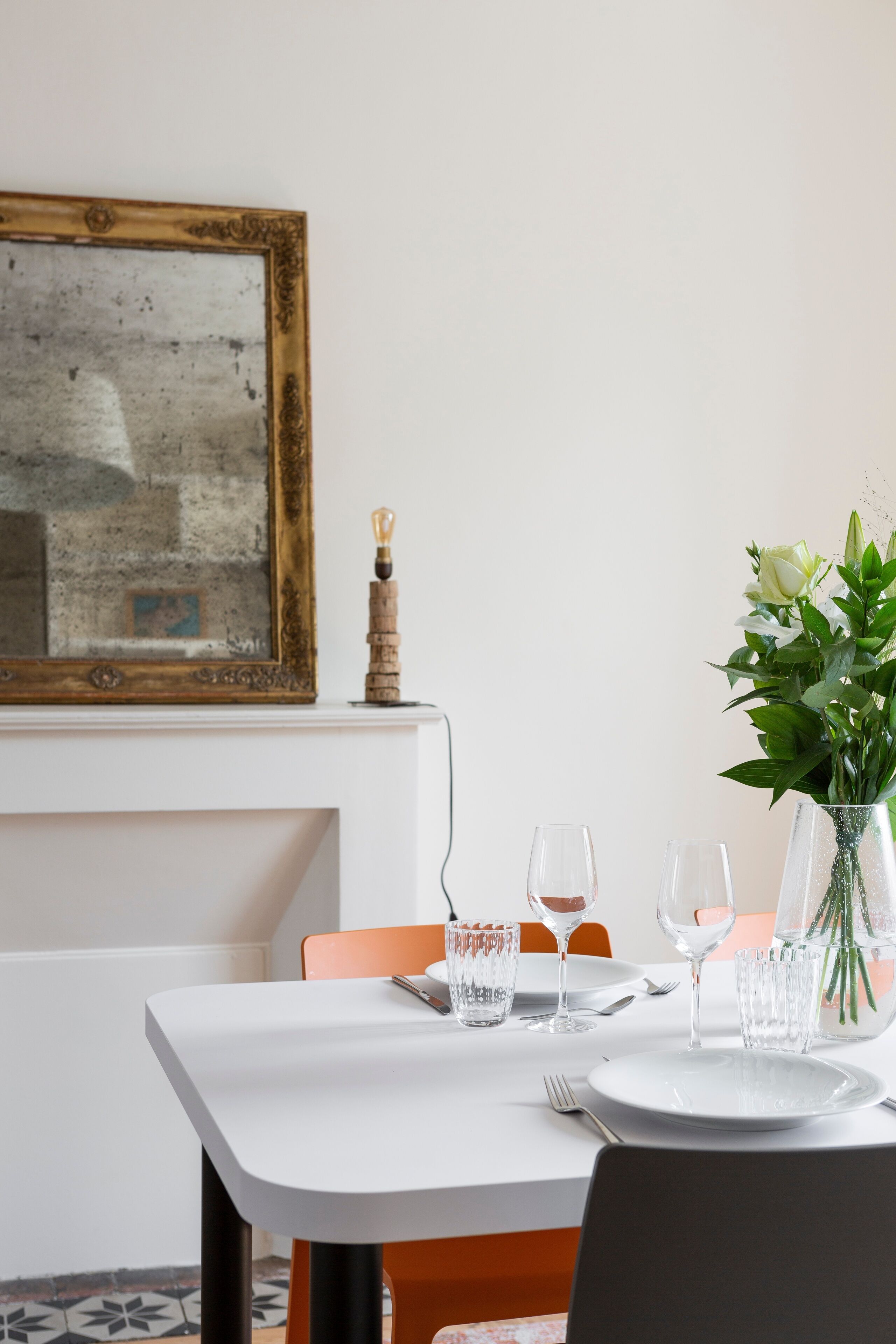 A dining table set with plates, glasses, and a vase of flowers.