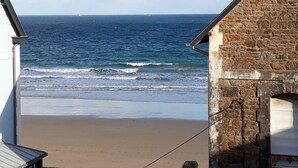 Vista de la playa con un edificio de piedra al frente.