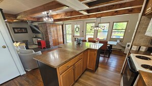 Une cuisine avec des meubles en bois, un grand îlot central, une cuisinière et un coin repas comprenant une table et des chaises.