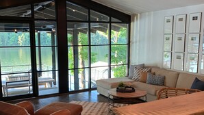 A spacious living room with a large window, a sofa, a coffee table, and a wooden table.