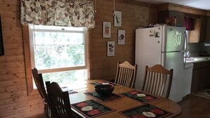 A wooden dining table with chairs, a bowl, and placemats with fruit designs.