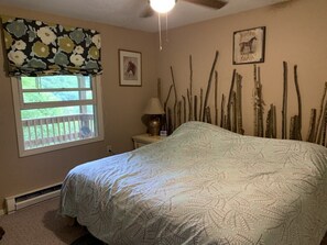 A bedroom with a bed, a window with a view, a lamp, and wall decorations.