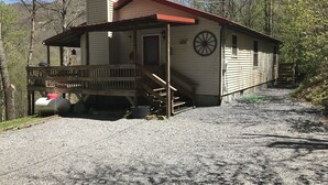 A single-story building with a porch, a chimney, and a wheel on the side.