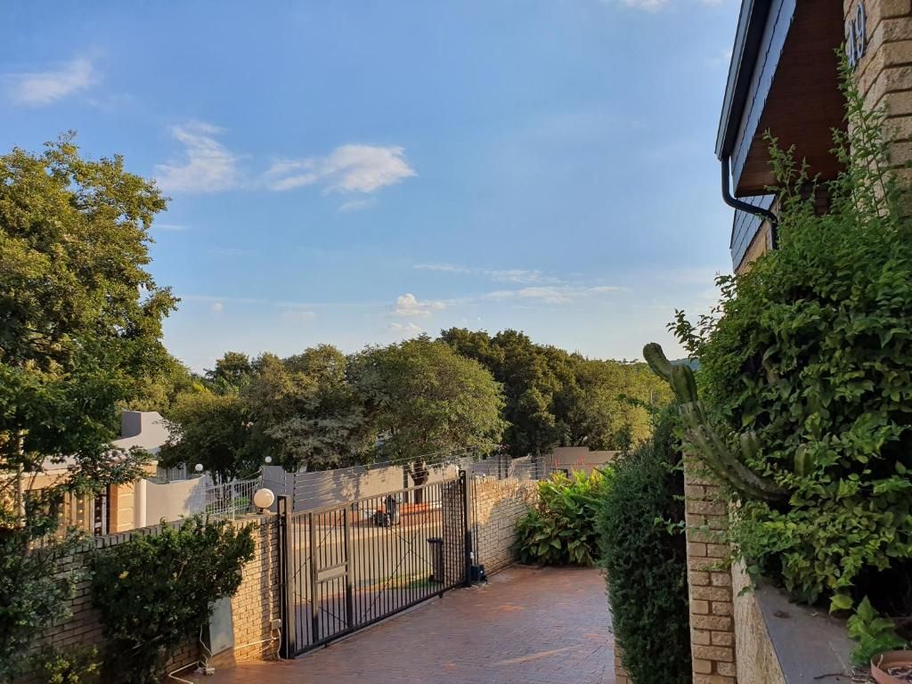 A gated courtyard with a brick wall, a metal gate, and lush greenery.