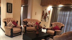 Una sala de estar con tres sillones, una mesa de centro y un jarrón con flores.