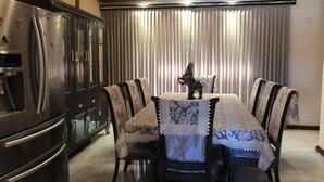 Un comedor con una mesa preparada para cuatro personas, rodeada de sillas tapizadas con un estampado decorativo. Una figurita ornamental de caballo está sobre la mesa.