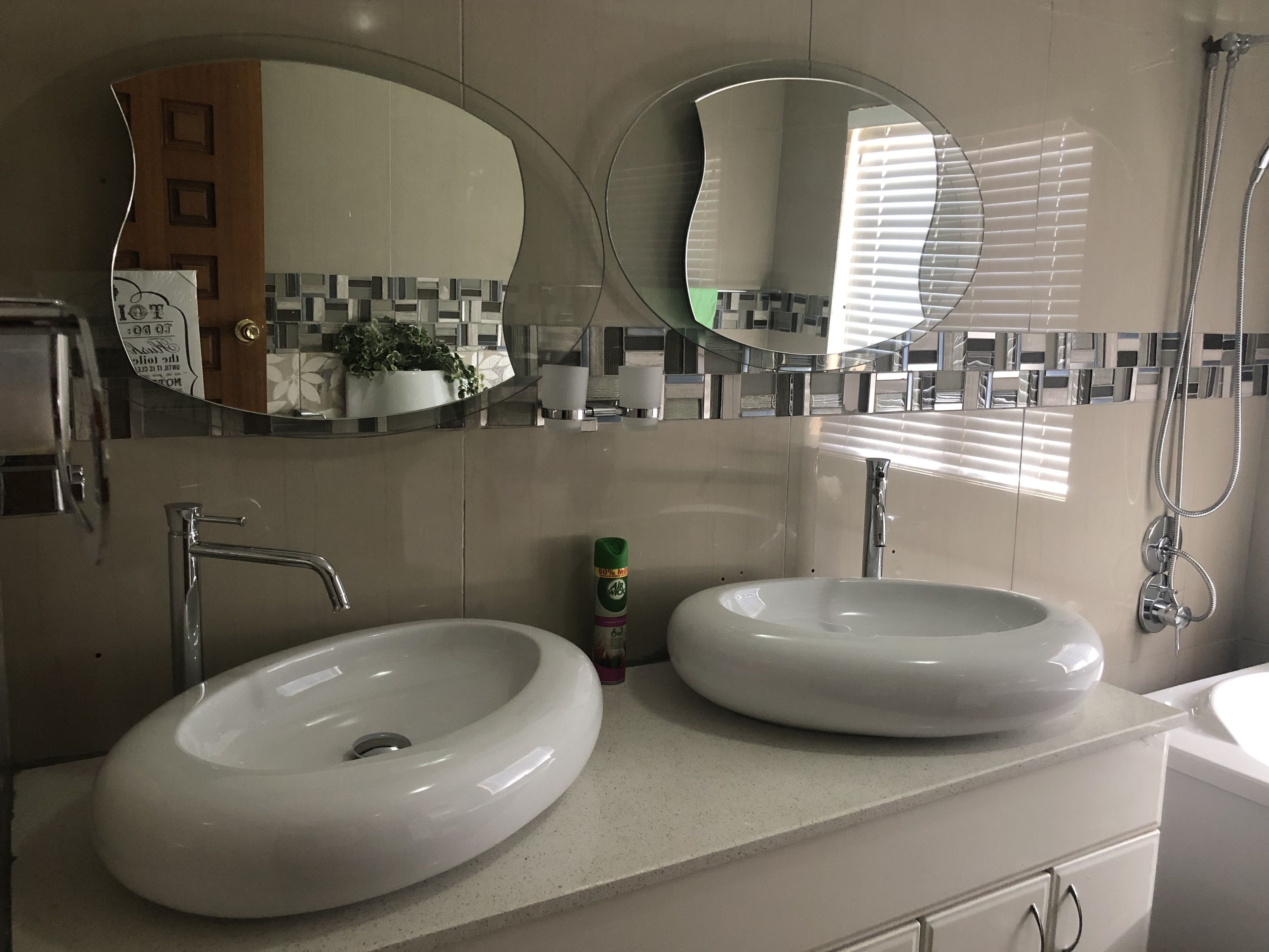 A modern bathroom with two sinks, a large mirror, and a shower.