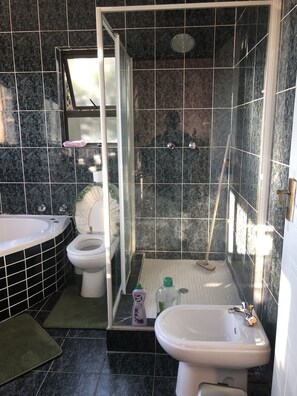 A bathroom with a bathtub, toilet, shower, and sink. - Naomi's Place (Johannesburg South)