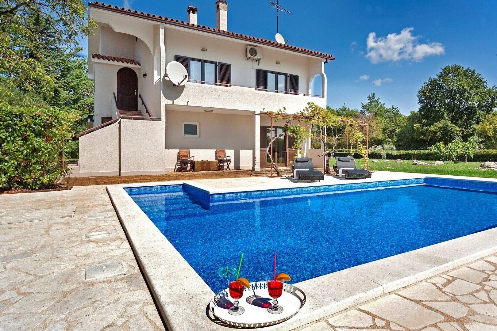A two-story house with a swimming pool, outdoor seating, and a satellite dish.
