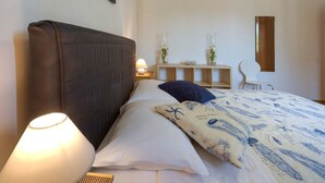 A bedroom with a large bed, a bedside lamp, a nightstand, a small table with decorative items, a chair, and a mirror on the wall. - ***Apartment with private pool and large garden (Nova Vas)