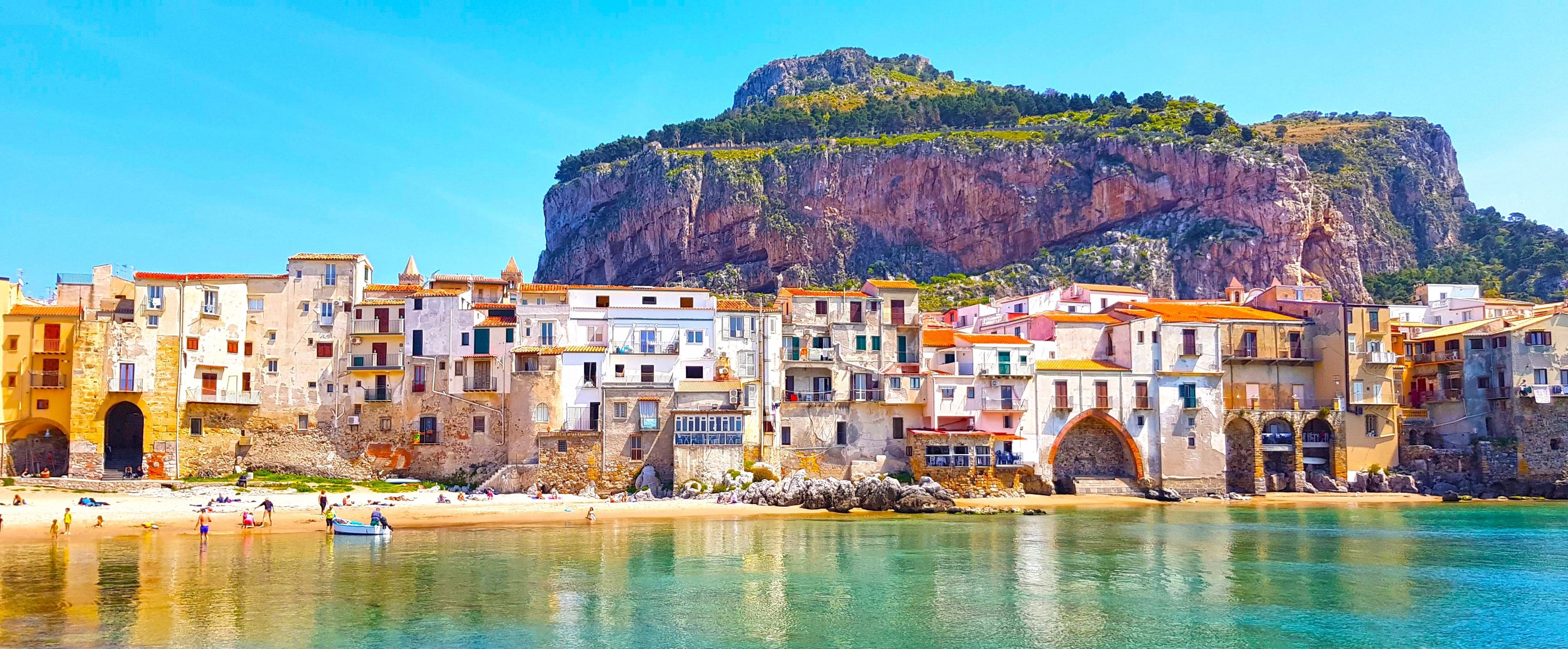 Un pueblo costero con edificios históricos, una playa y un acantilado imponente.