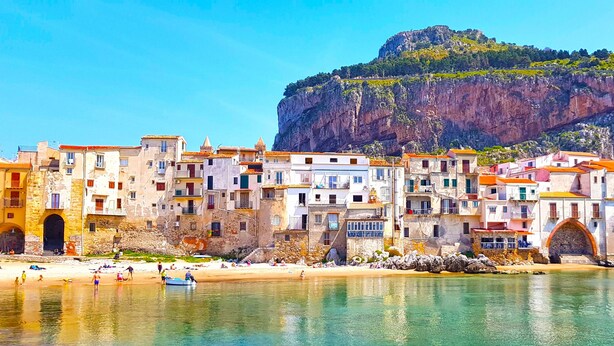 A coastal town with historic buildings, a beach, and a prominent cliff.