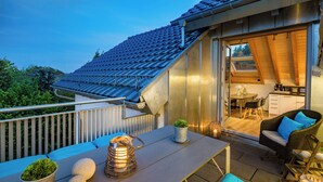 A modern outdoor patio area with a dining table, chairs, and a small kitchen visible through an open door. - 5* rooftop loft with roof terrace to enjoy /1-4 p/ garden use/parking/close to the city (Bensheim)