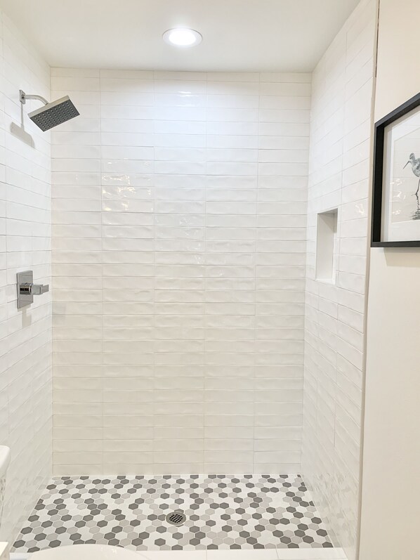 A shower with white tiles and a hexagonal patterned floor. - Sea It All - 5 BR 2 GOLF CARTS Lakefront House w Golf Cart in Sandestin Resort (Miramar Beach)