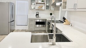 A modern kitchen with stainless steel appliances, a built-in oven, a coffee maker, and a sink with a flexible faucet.