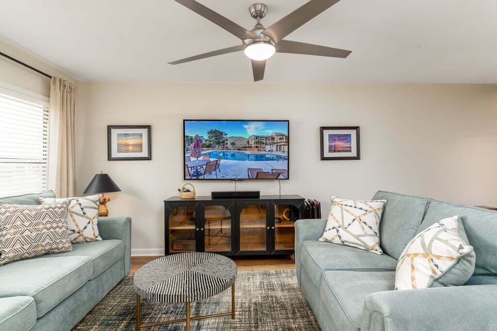 A living room with a sofa, a coffee table, a TV, and a ceiling fan.